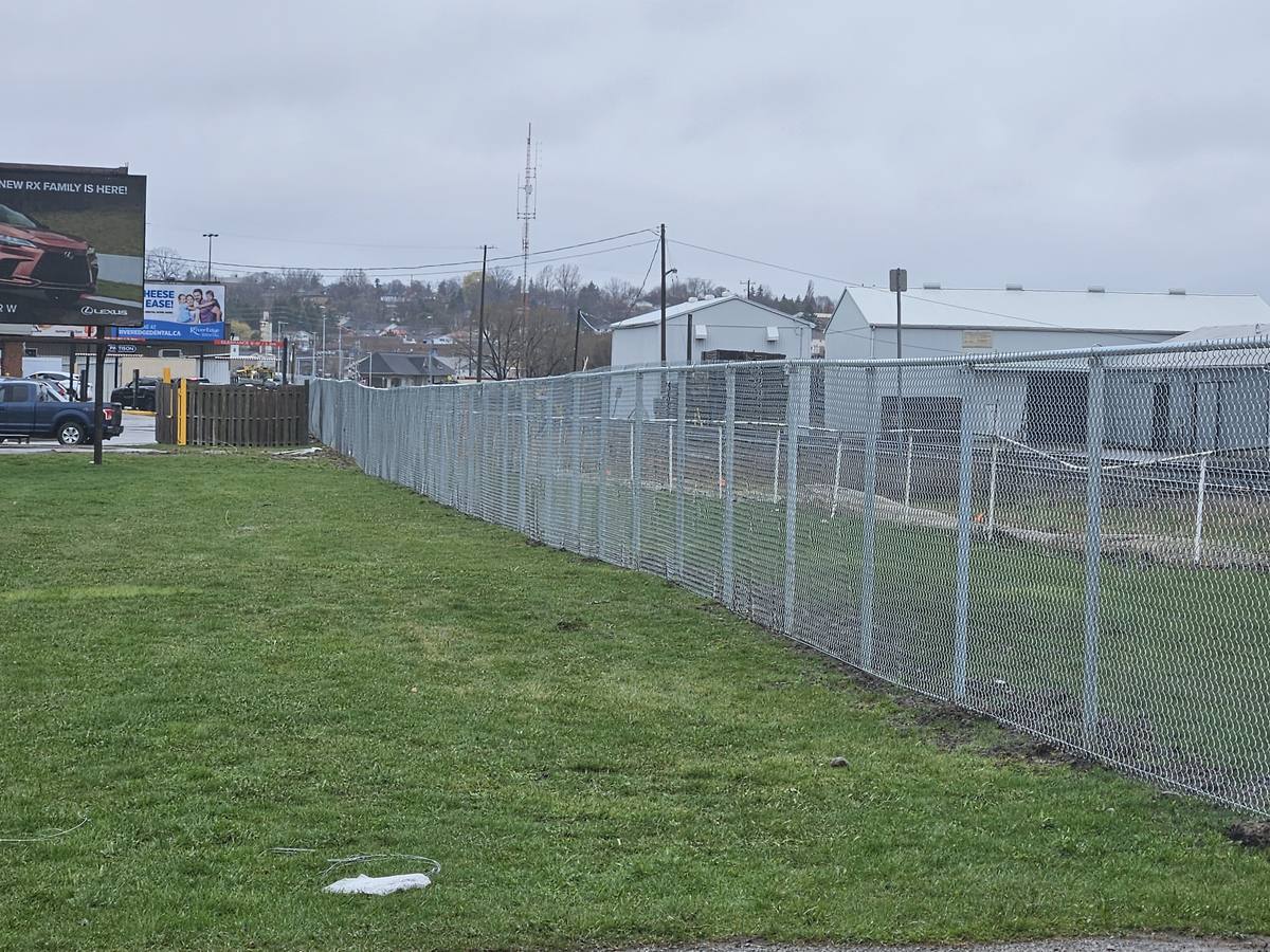 New galvanized chain link fence along a grass boulevard